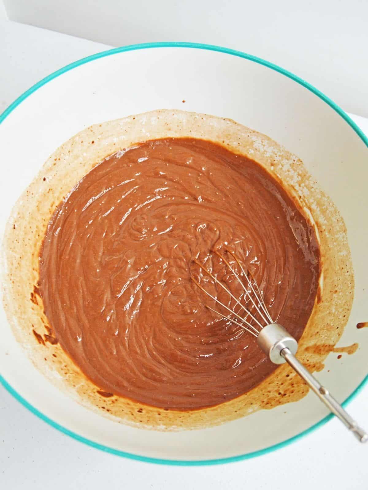 chocolate pudding in bowl with wire whisk.