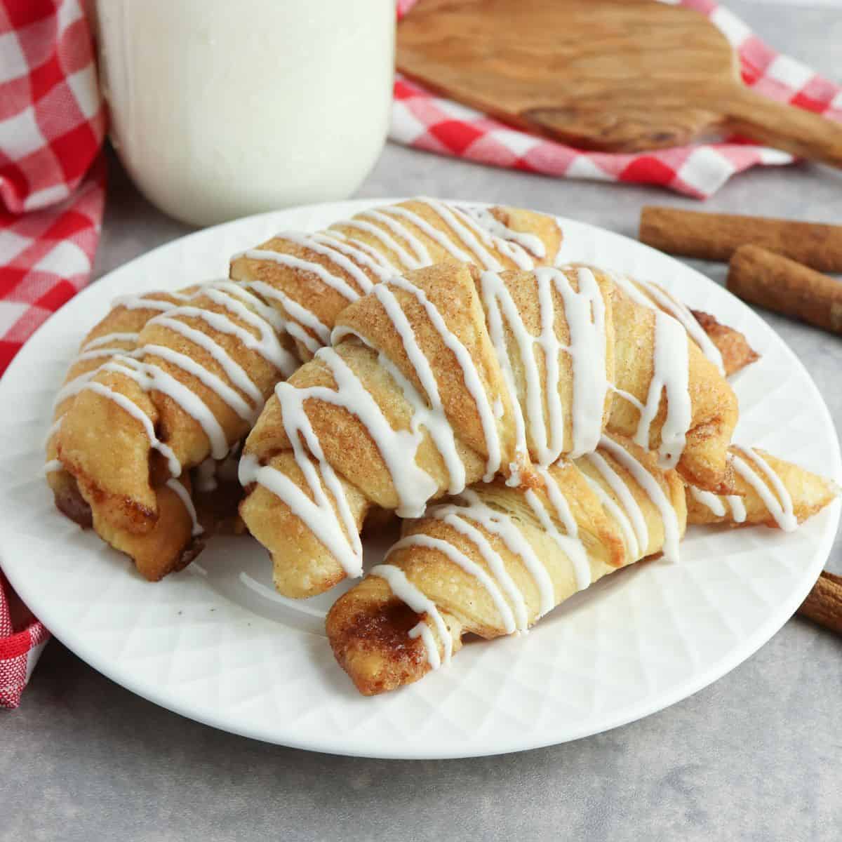 square photo of Pillsbury crescent rolls with cinnamon sugar mixture on white plate.
