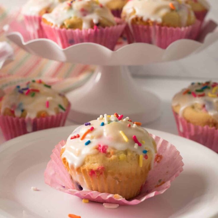 Muffins with sprinkles and glaze on plates.