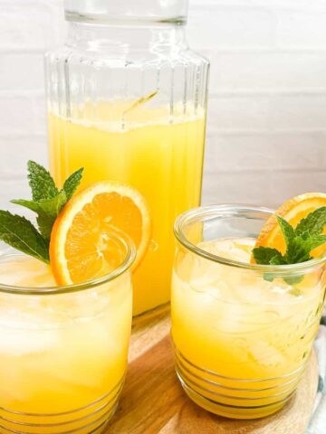 2 glasses of tropical orange punch with pitcher.
