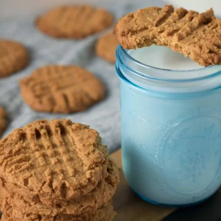 glass of milk in blue mason jar with peanut butter cookies.