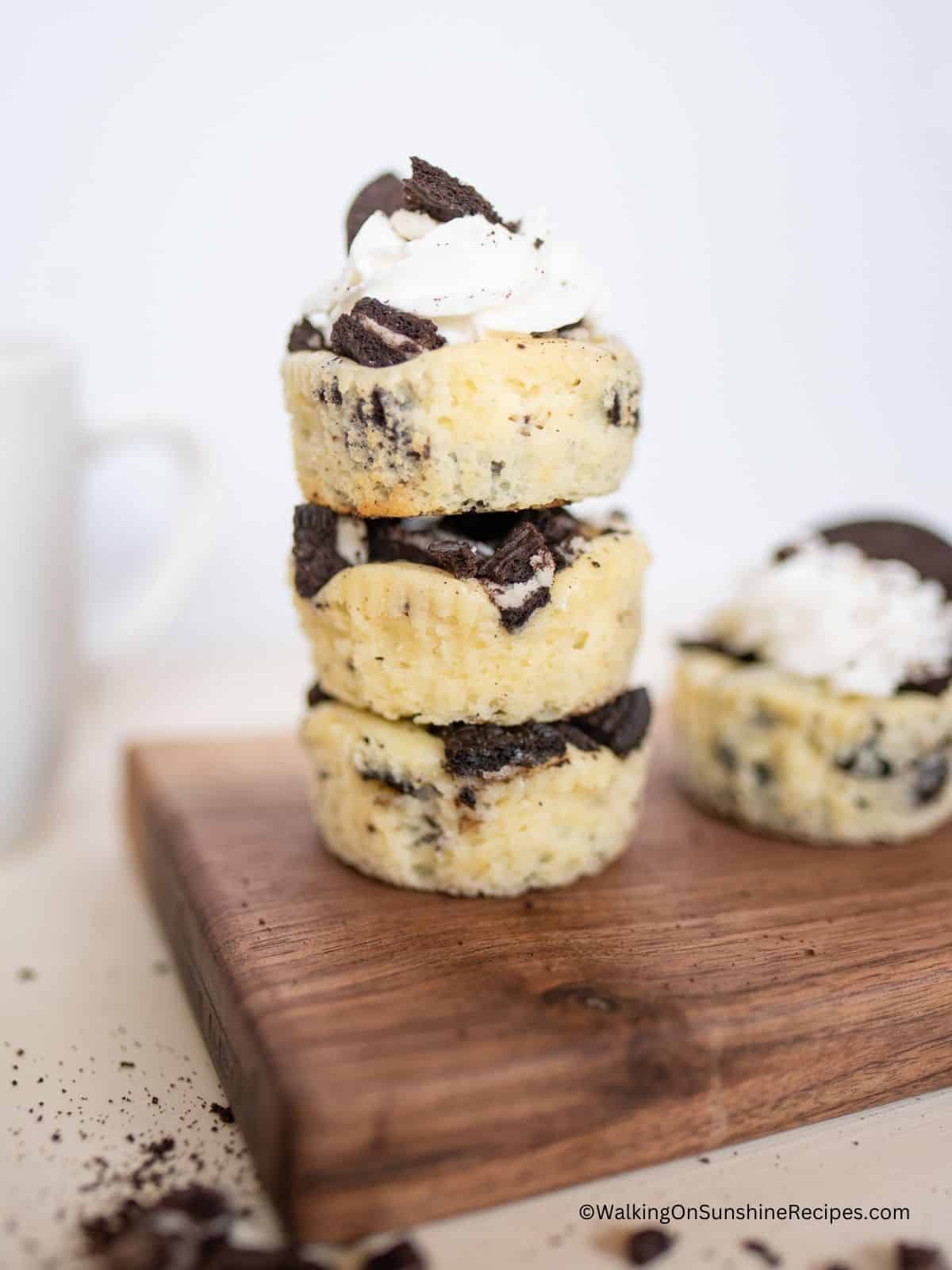 Mini cookie cheesecakes stacked on cutting board.