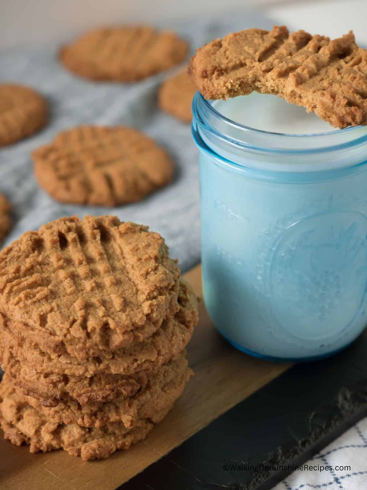 peanut butter cookie with bite on top of mason jar filled with milk.