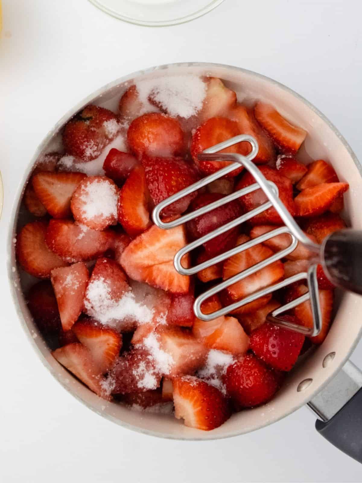mash strawberries with potato masher.