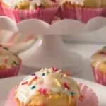 muffins with powdered sugar glaze and rainbow sprinkles on dessert plate and on individual plate.