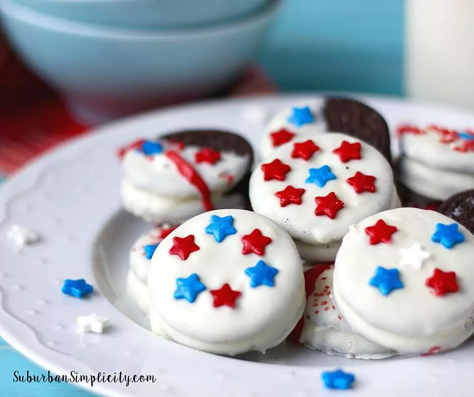 Oreo cookies dipped in white chocolate decorated with red, blue and white star shaped sprinkles.
