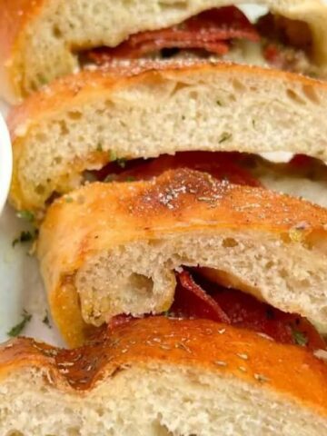 A loaf of pizza bread filled with pepperoni, sausage, and cheese.