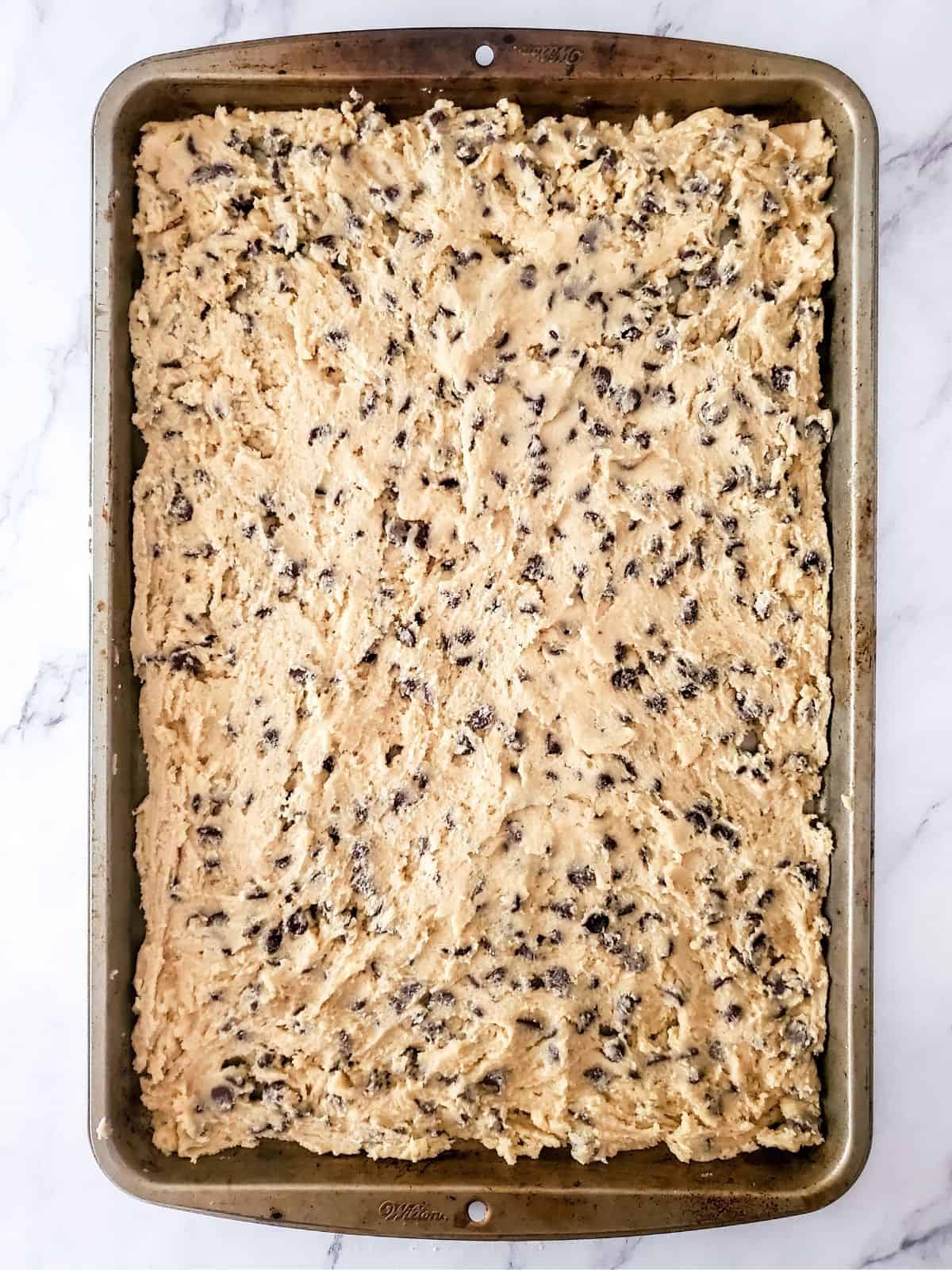 raw cookie dough spread in sheet pan.