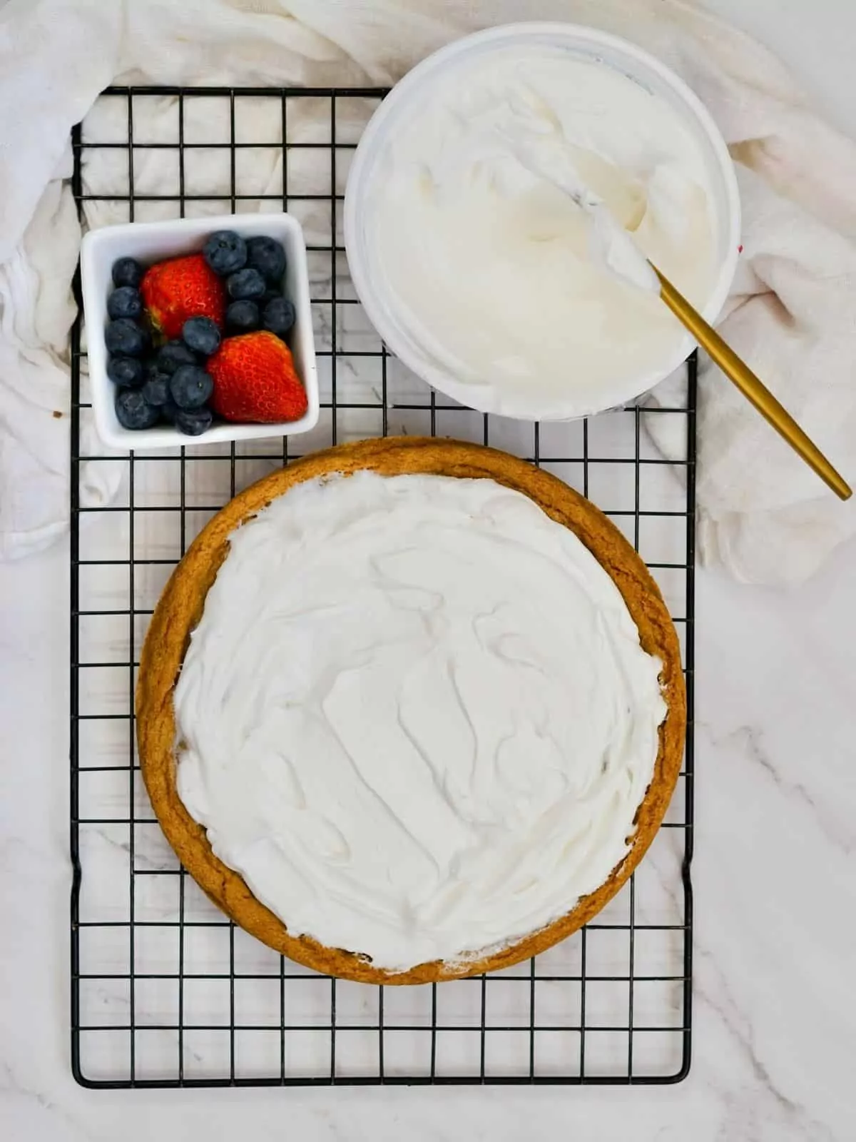 Cool Whip Whipped topping spread on top of sugar cookie pizza.