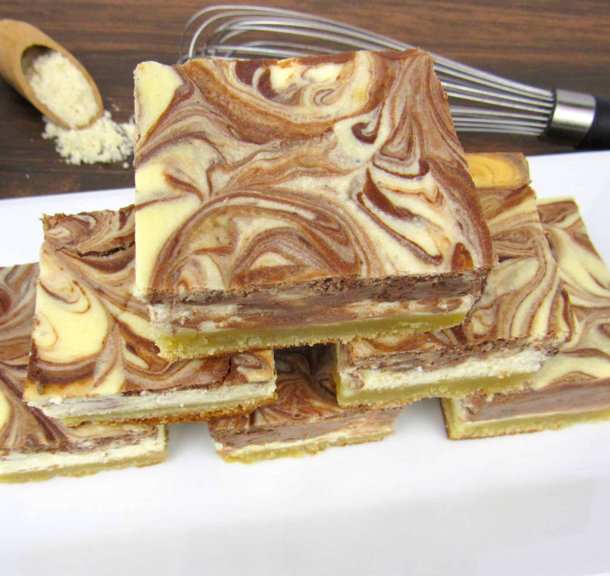vanilla and chocolate cheesecake swirl bars stacked on top of each other.