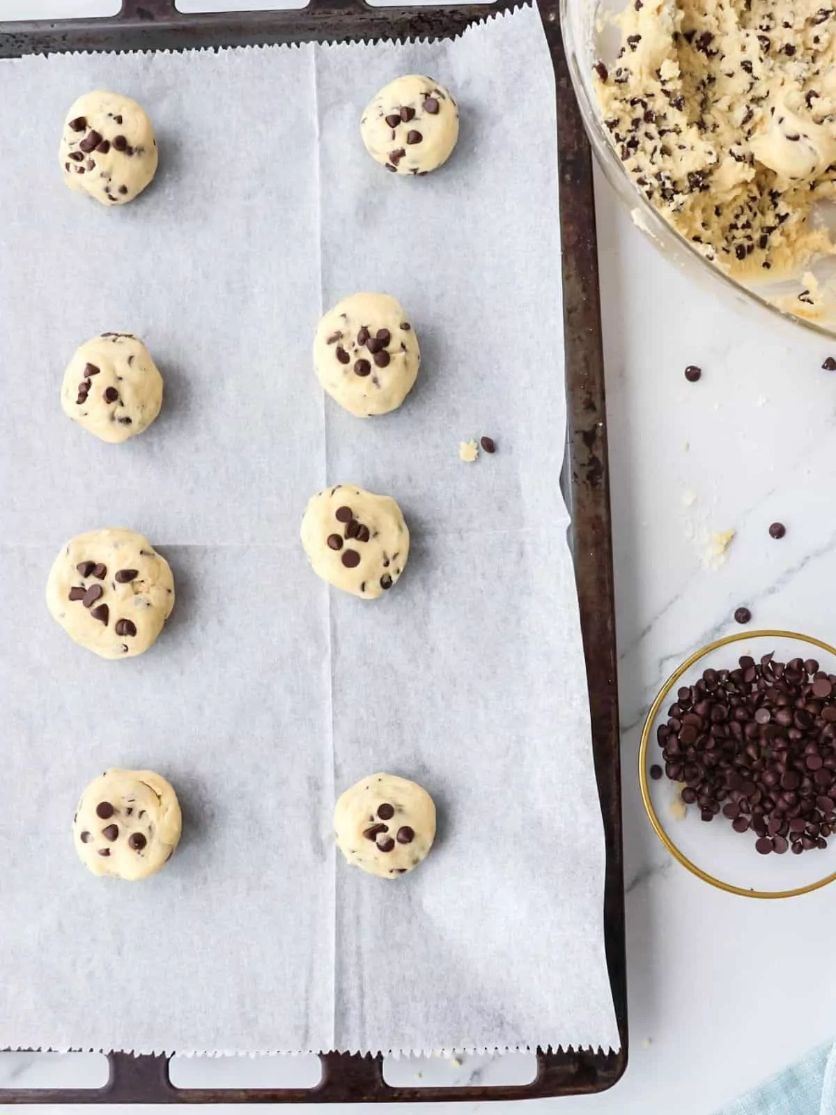 chocolate chip cookie balls on baking tray with parchment paper.