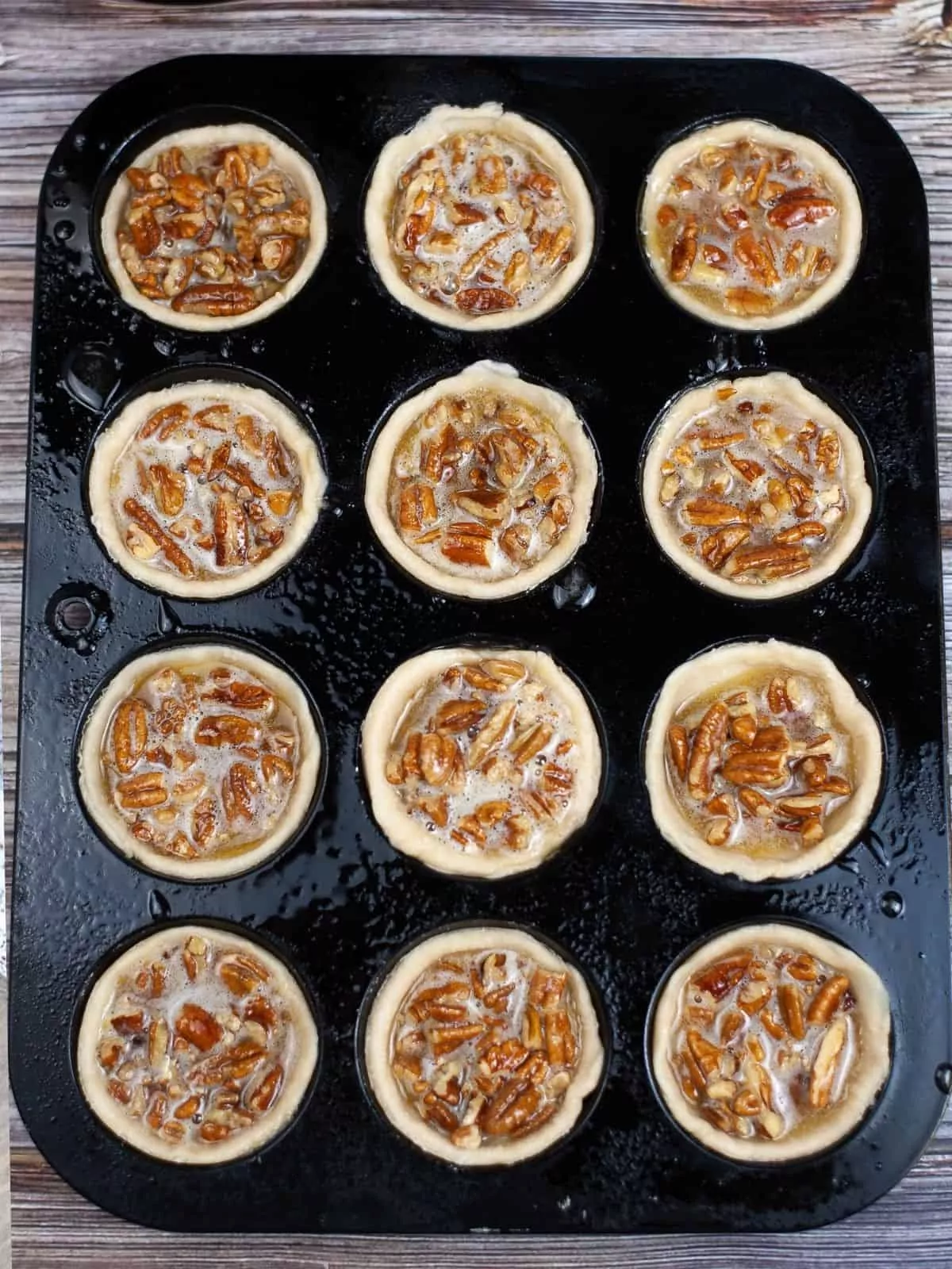 unbaked pecan pie tartlets in muffin pan.