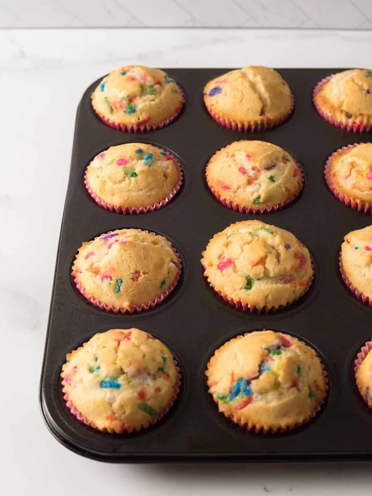 baked muffins with rainbow sprinkles in muffin pan.