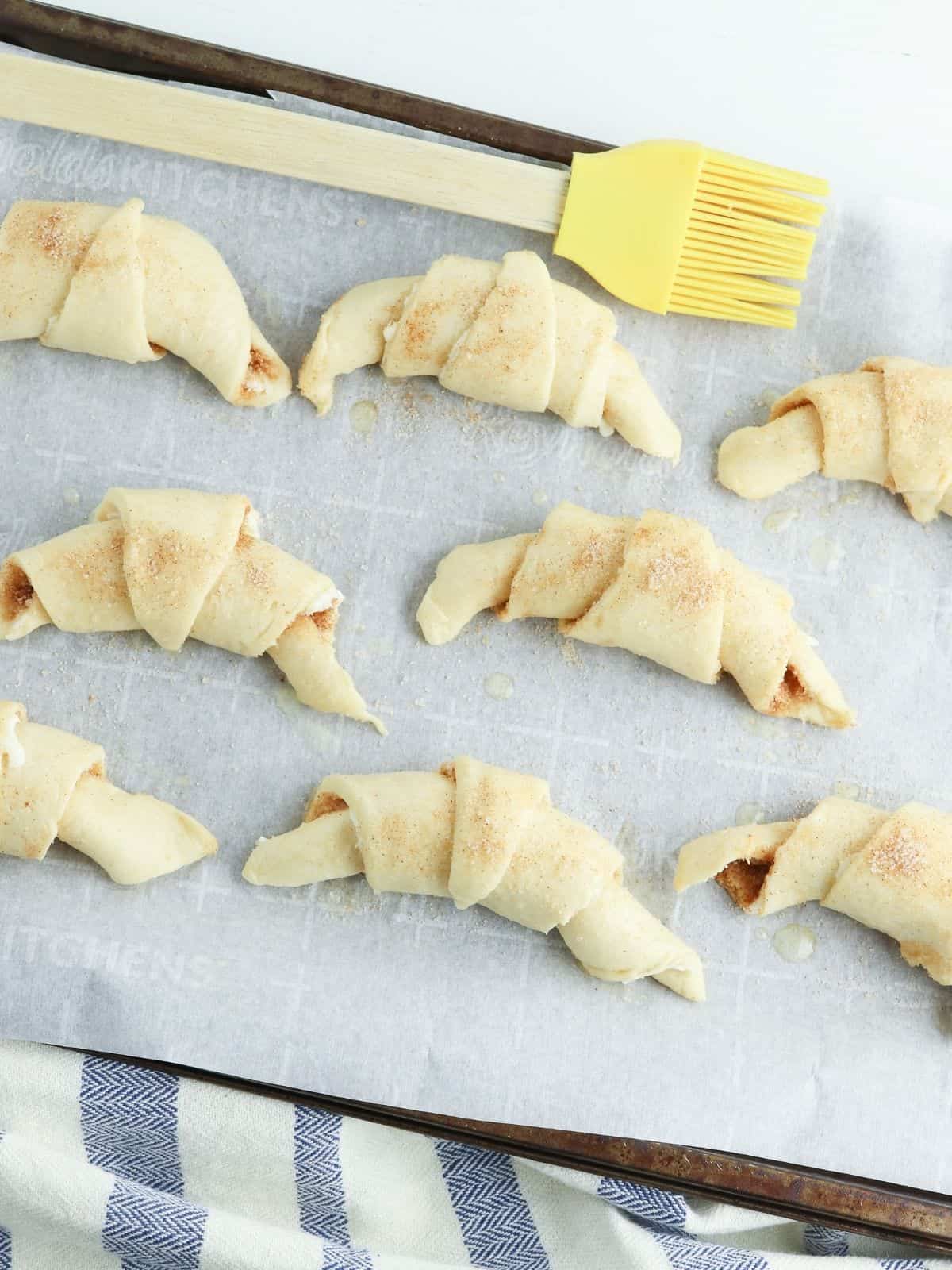 rolled up crescent rolls on baking tray lined with parchment paper.