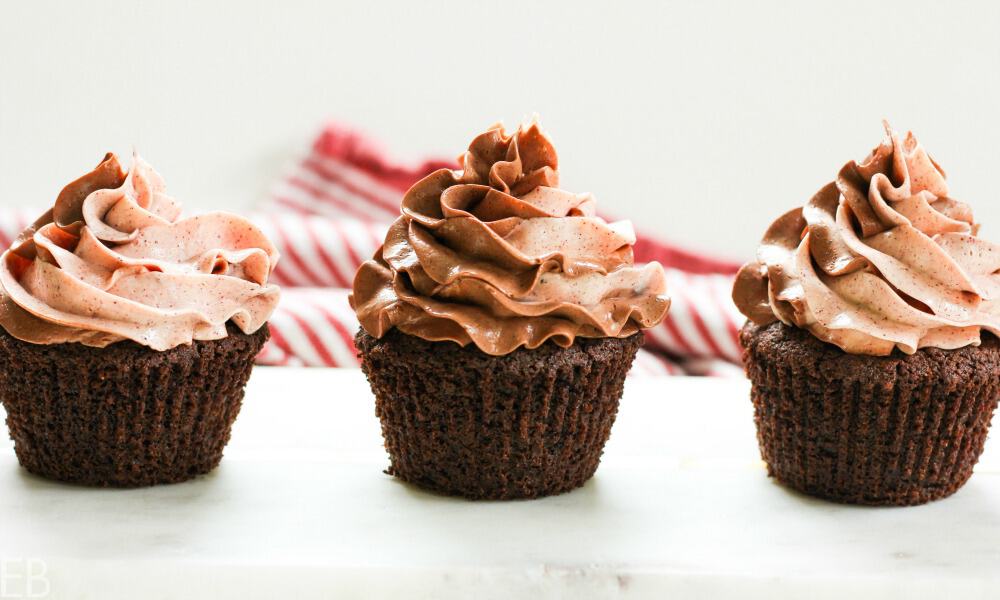3 chocolate cupcakes with chocolate frosting swirled on top.