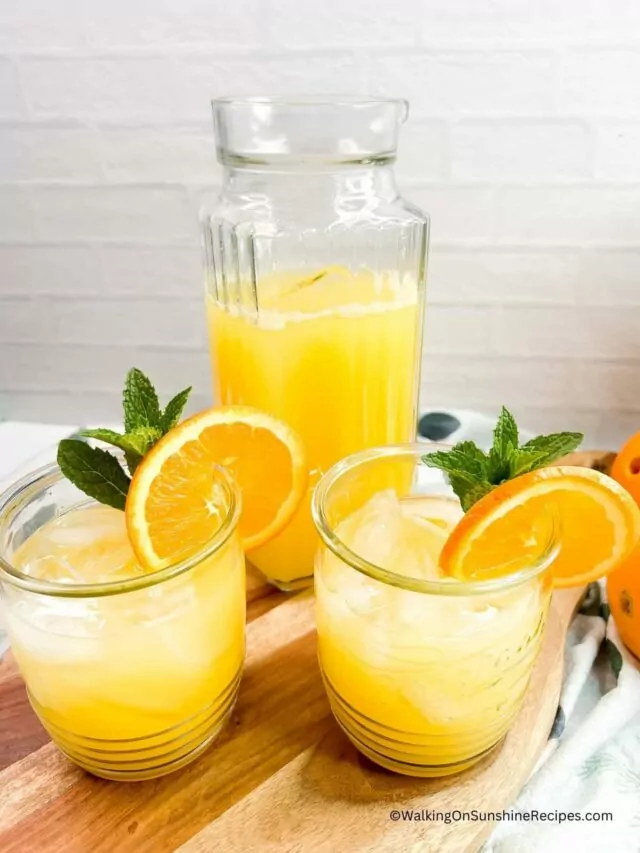 tall pitcher and two glasses filled with Orange pineapple punch.