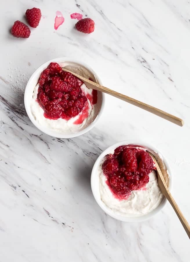 2 bowls of cheesecake with raspberry fruit on top.
