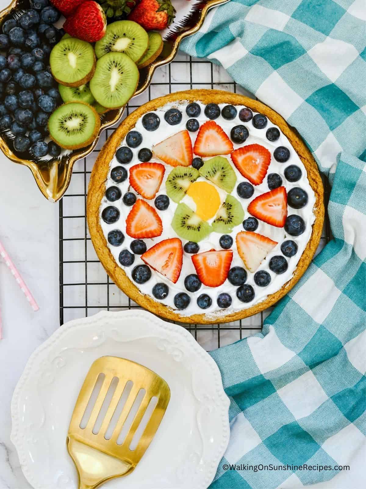 Pizza made with cookie dough and topped with strawberries, blueberries, kiwi and oranges.