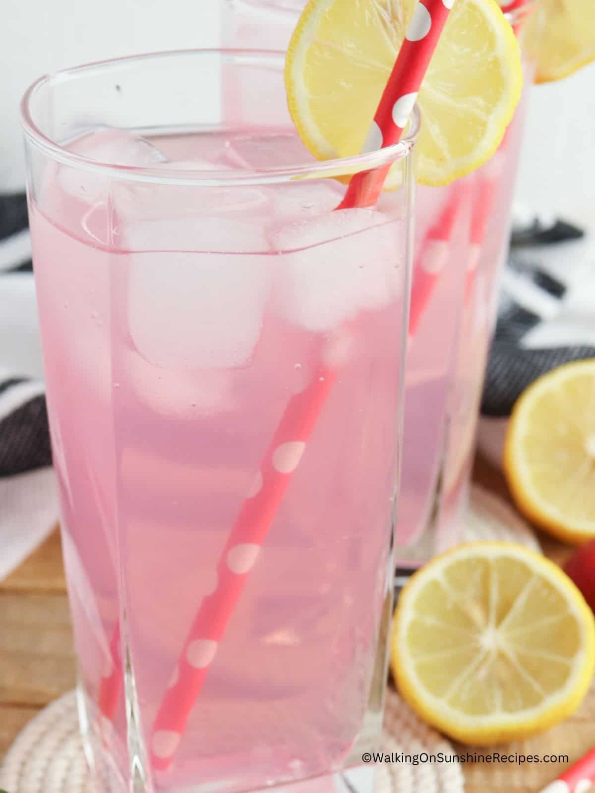 strawberry punch lemonade in tall glass with straw.