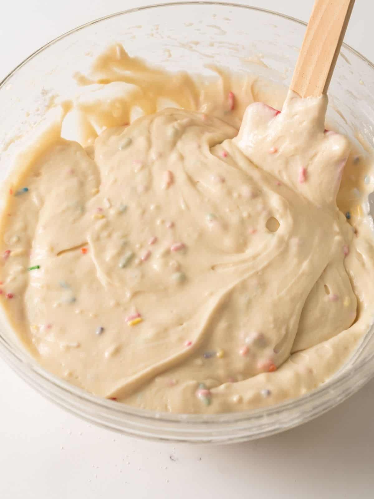 homemade muffin batter in bowl with rainbow sprinkles.