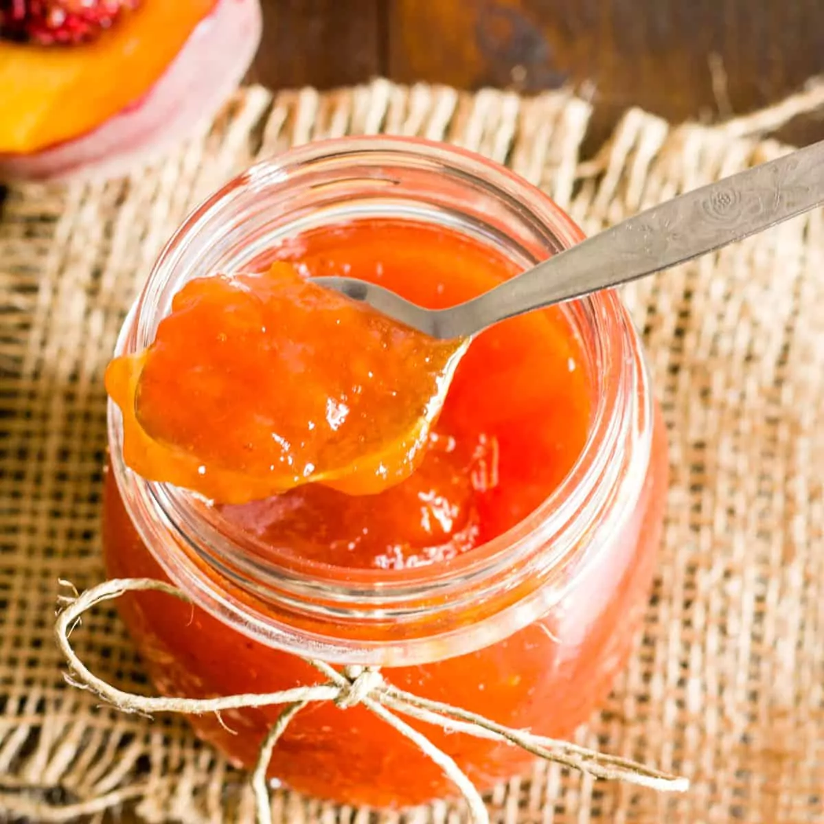 peach jam in jar with spoon.