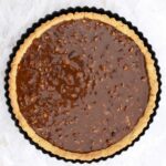 pecan pie filling in pre-baked pie crust shell ready for oven.