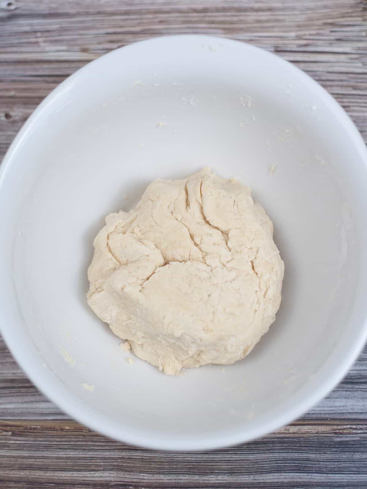 pie dough formed into ball in white bowl.