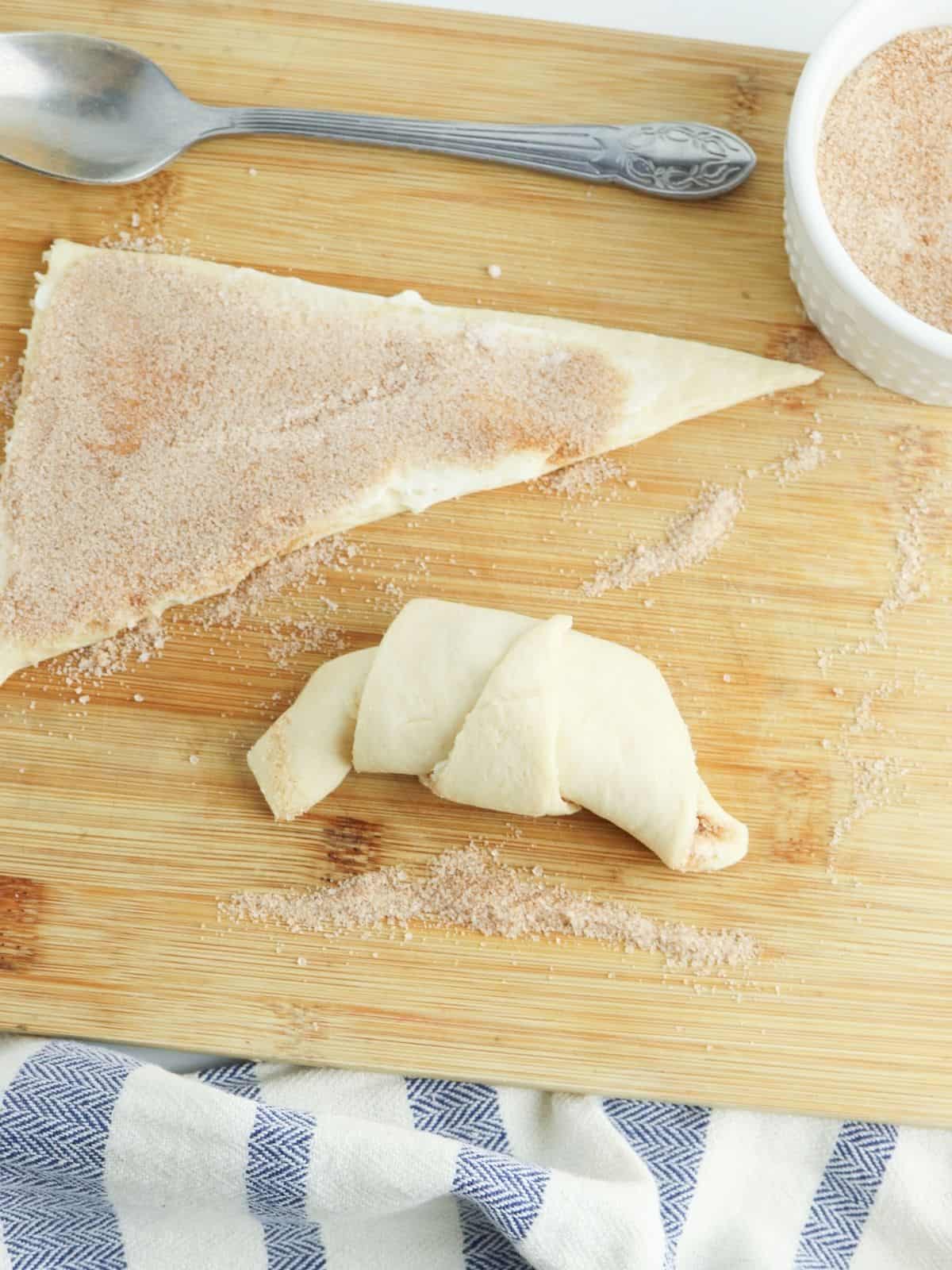 one crescent roll rolled up and one open with cinnamon sugar mixture.