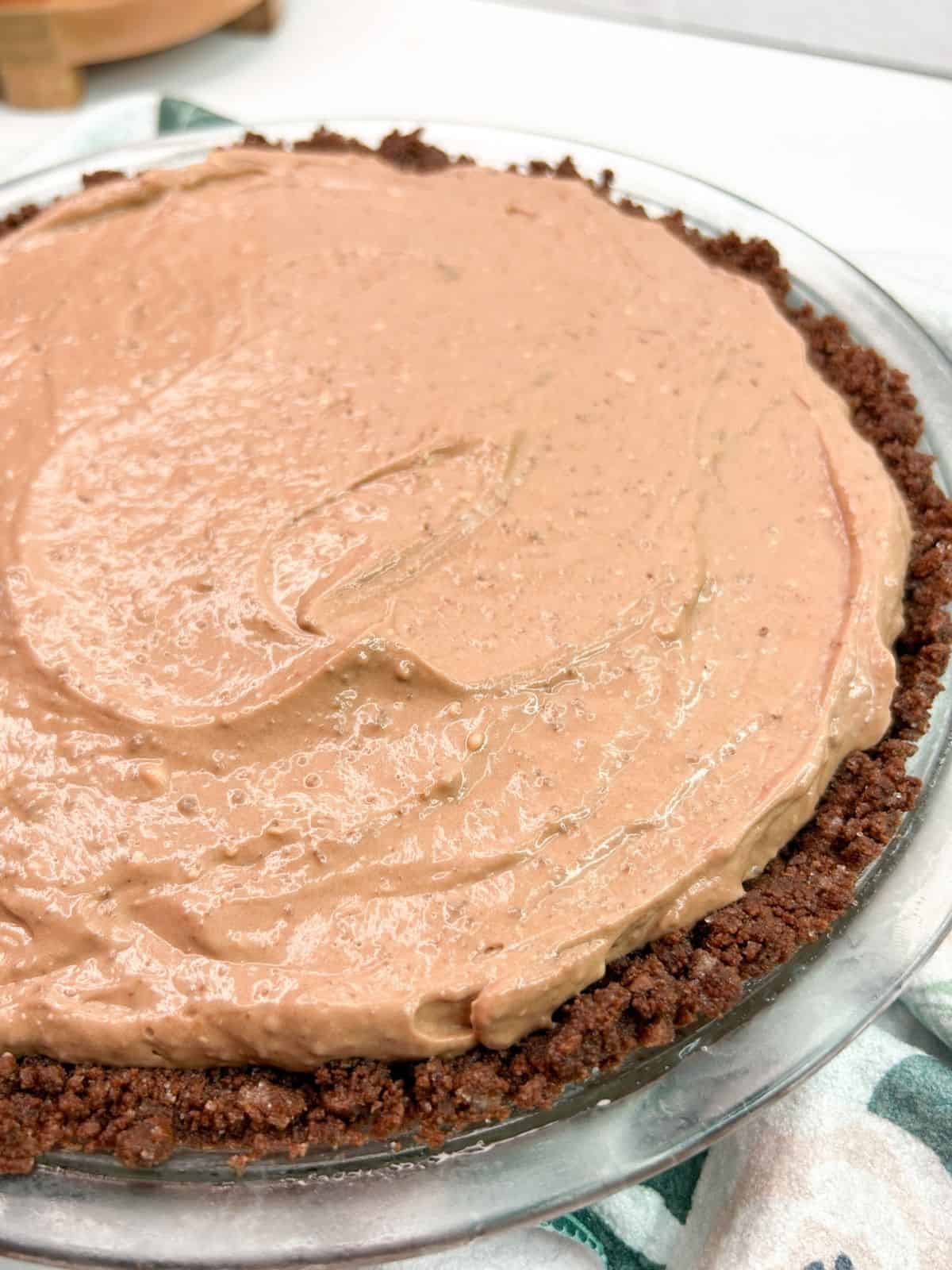 chocolate pudding pie mixture with graham cracker crumbs in pie plate.