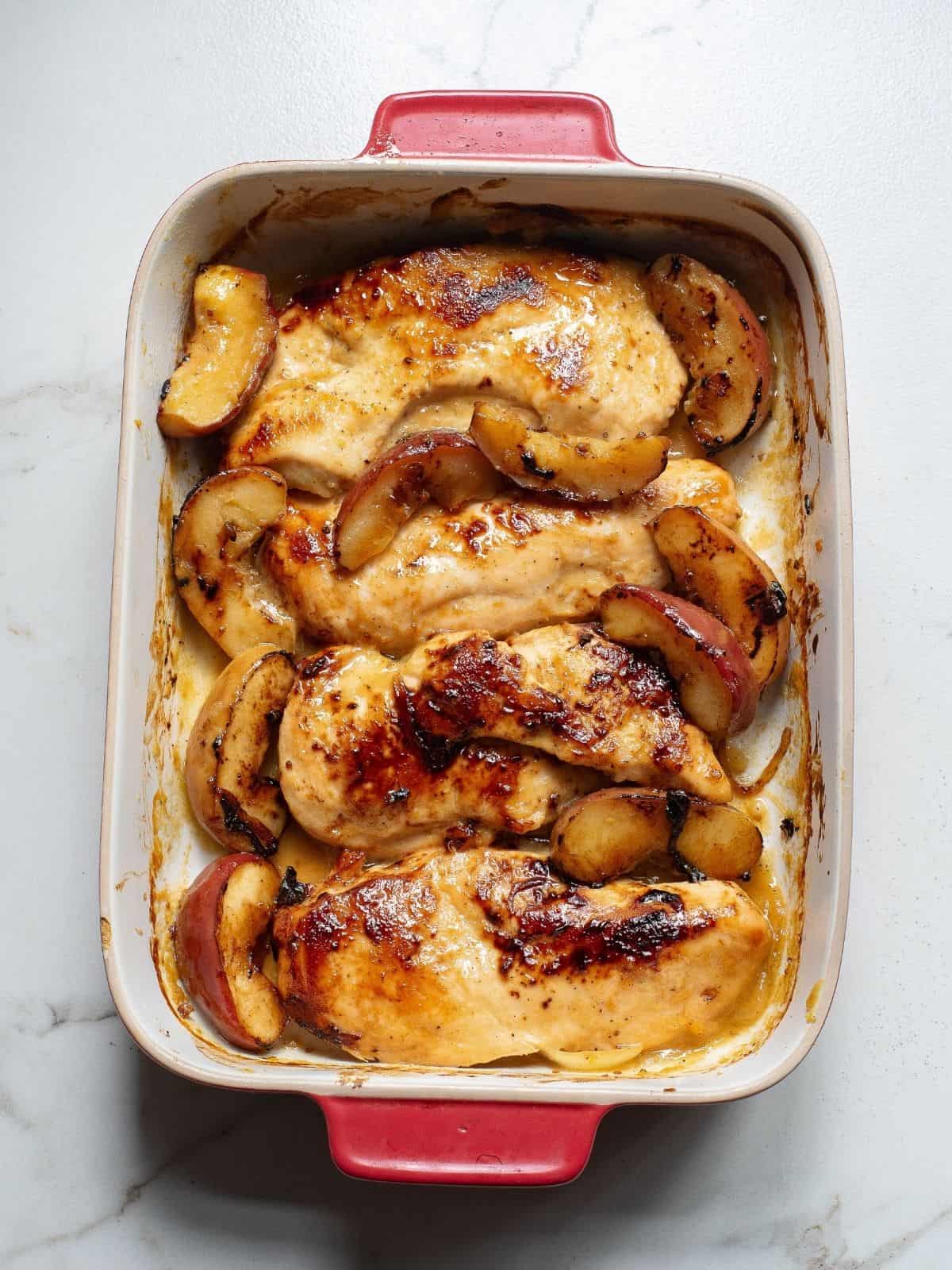 baked chicken with apples in baking dish.