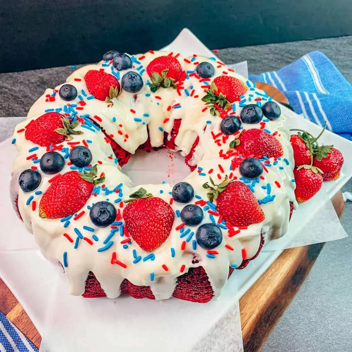 patriotic cake decorated with strawberries, blueberries and sprinkles.