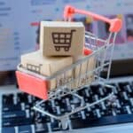 small shopping cart with small Amazon boxes on top of laptop.
