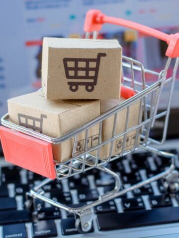 small shopping cart with small Amazon boxes on top of laptop.