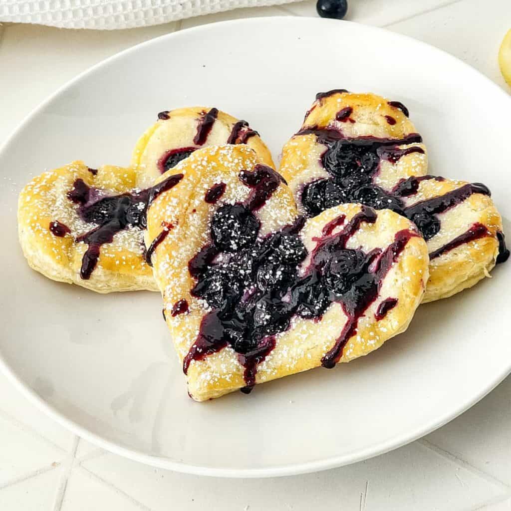 Blueberry Puff Pastry Danish on White Plate with powdered sugar.