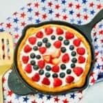 Strawberries, raspberries and blueberries on sugar cookie base in cast iron skillet.