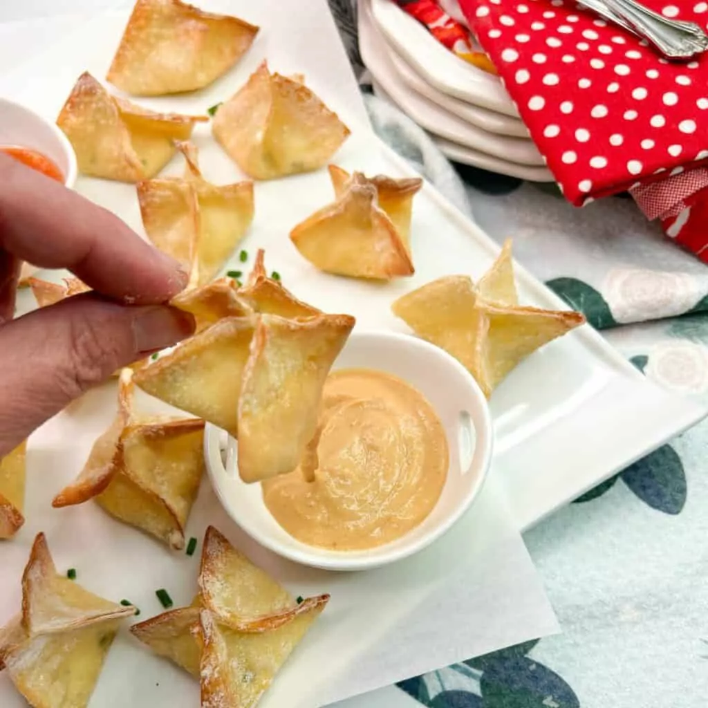 closeup of won ton held over hot mustard in small bowl.