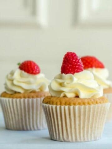 vanilla cupcake with cream cheese frosting and fresh raspberry.