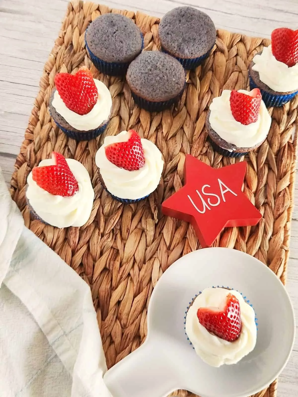 red, white and blue frosted cupcakes on woven mat and white plate.