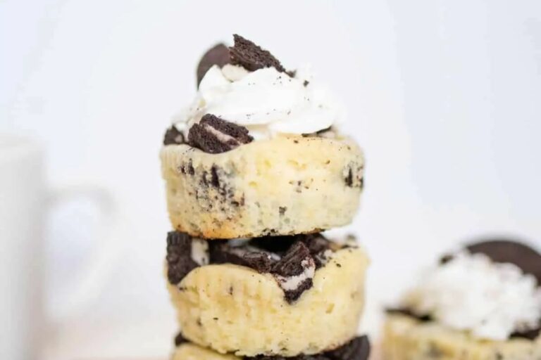 Three mini Oreo cheesecakes stacked on a wooden board.