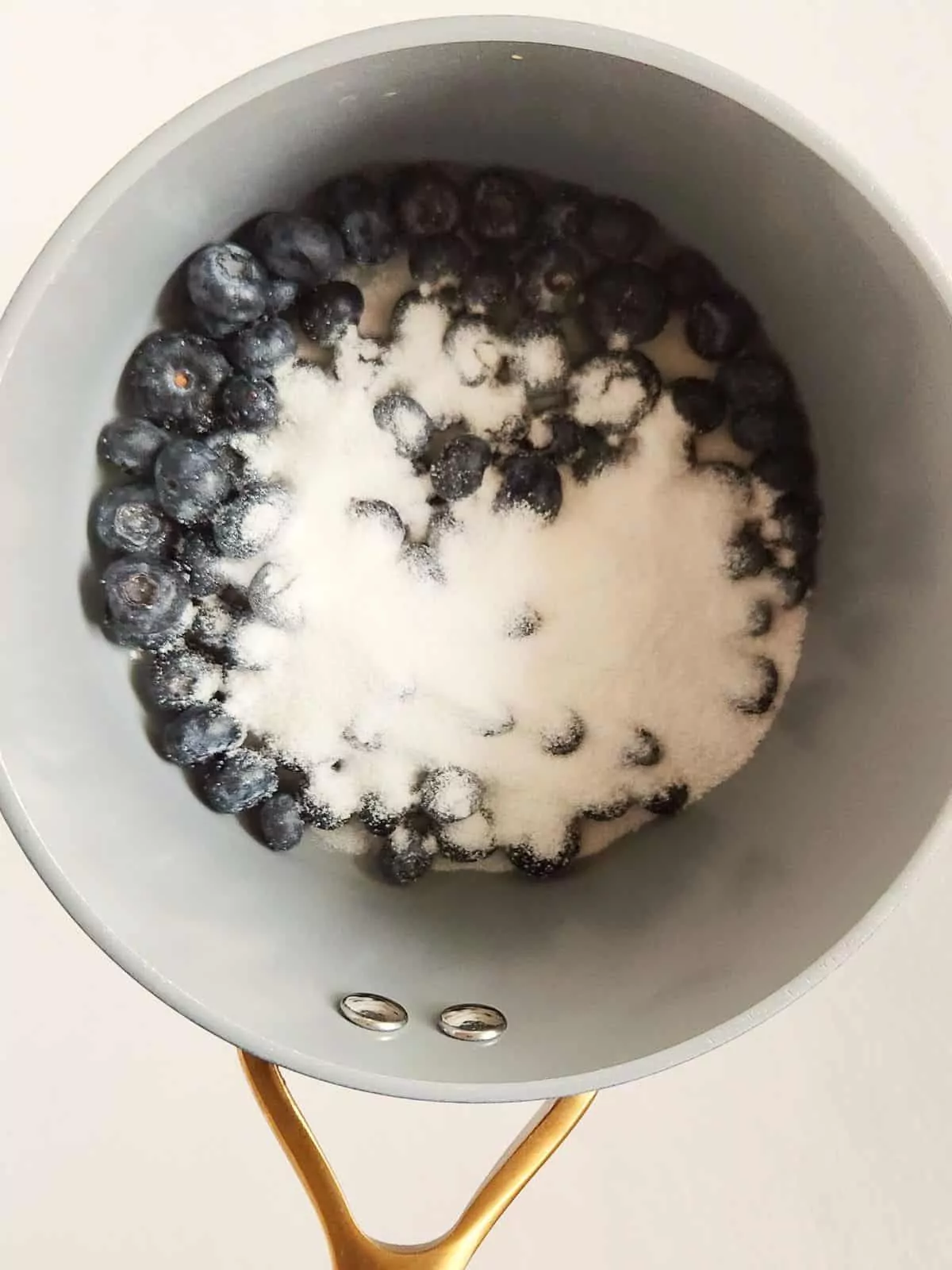 Blueberries and sugar in saucepan.