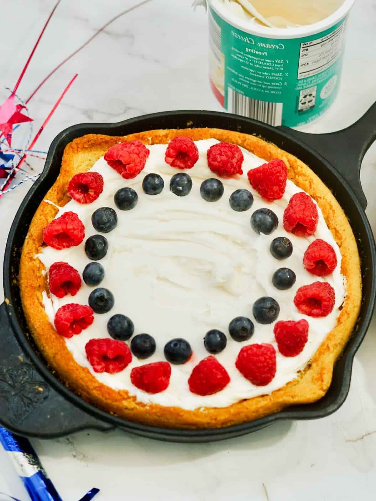Patriotic Cake in Cast Iron Skillet with raspberries and blueberries.