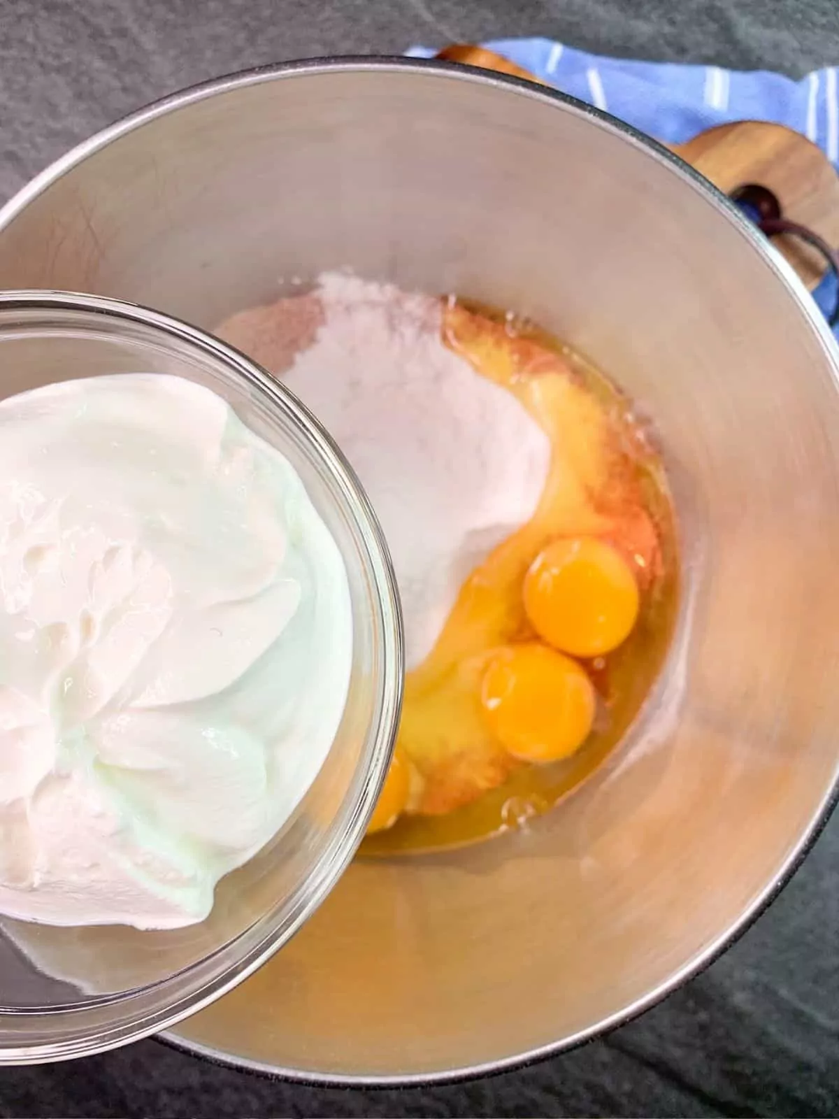 Adding sour cream to cake mix in mixing bowl.