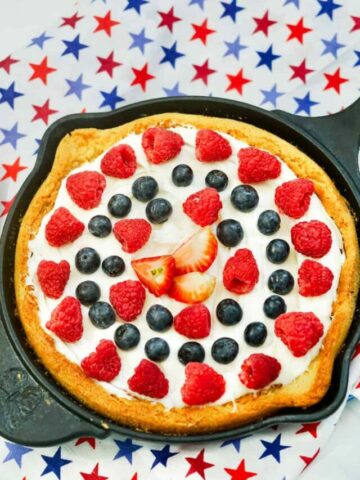 Strawberries, raspberries and blueberries on sugar cookie base in cast iron skillet.