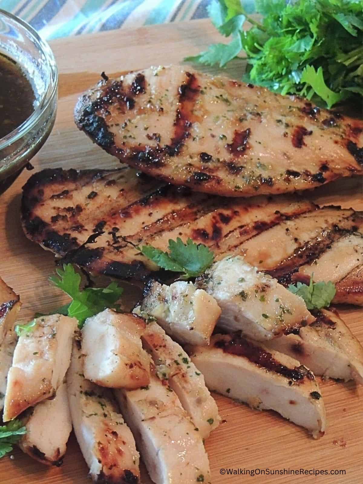 sliced grilled chicken with marinade in small bowl.