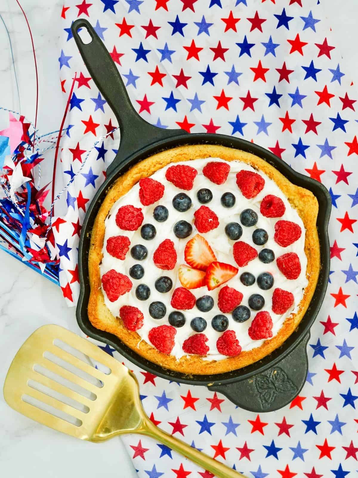 cookie cake in cast iron skillet on towel decorated with stars.