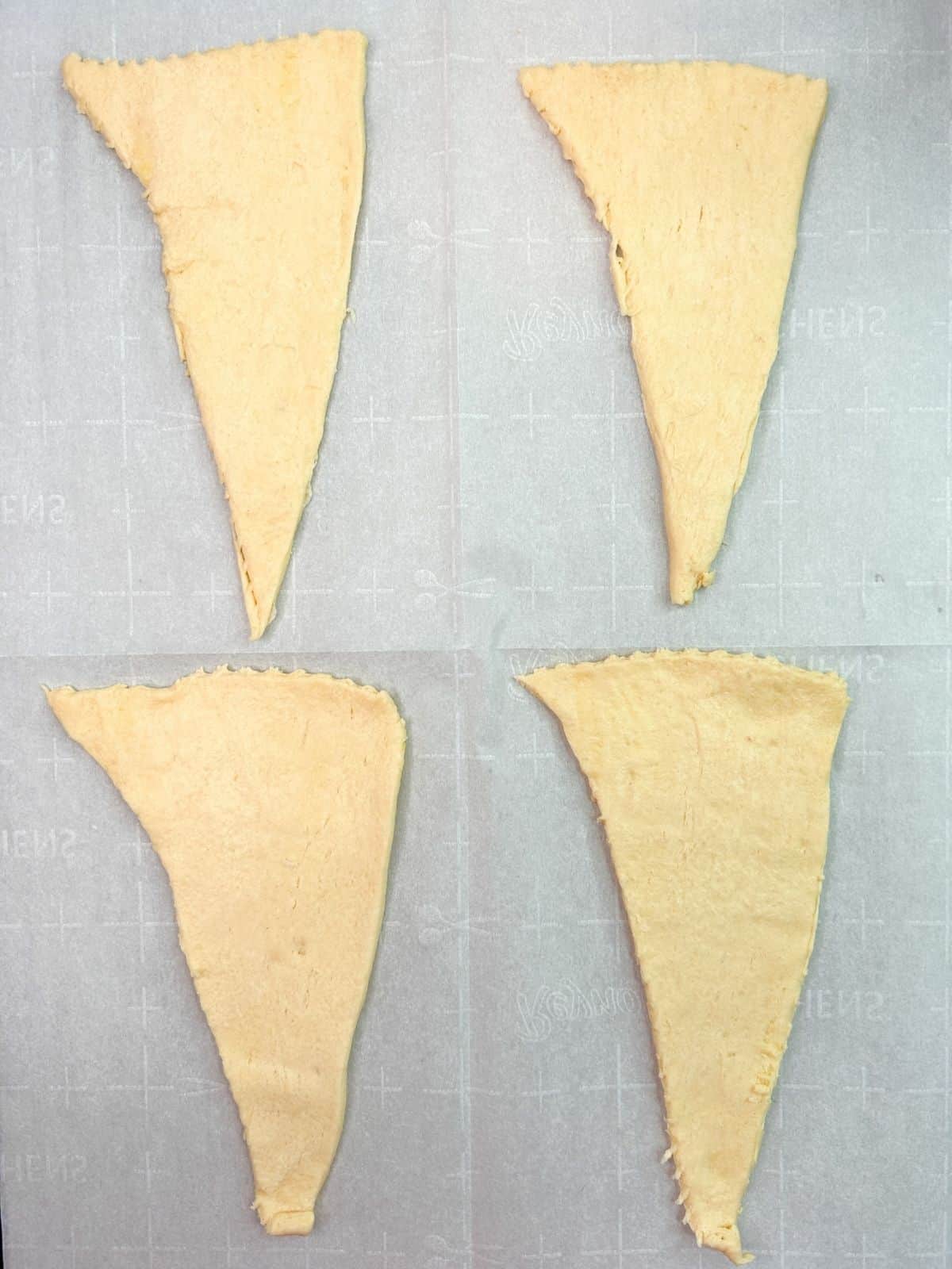 4 triangle crescent rolls on parchment paper.