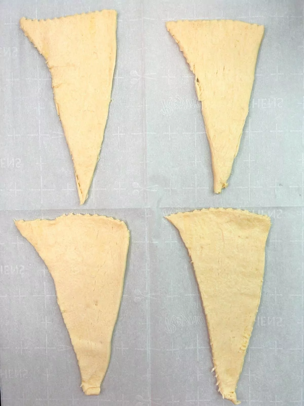 4 triangle crescent rolls on parchment paper.