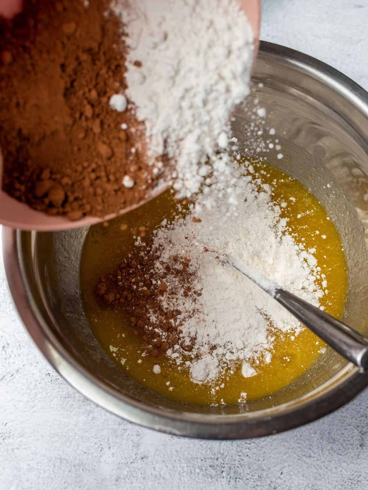 Add dry ingredients to wet ingredients for homemade chocolate brownies.