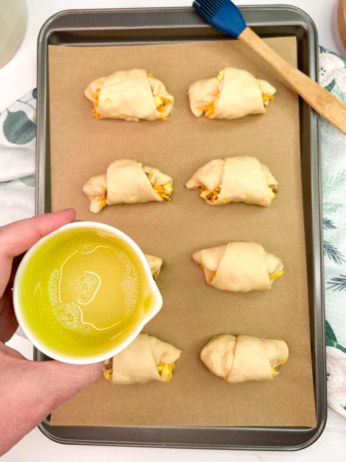 egg wash in small bowl over crescent rolls on baking tray.
