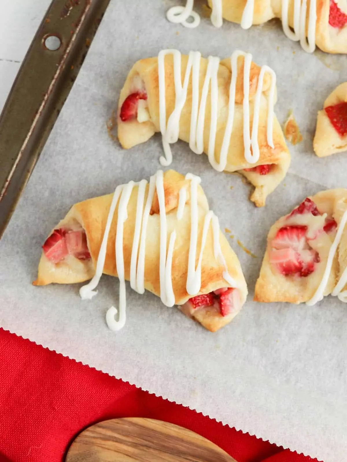 Crescent rolls filled with strawberries on baking tray.